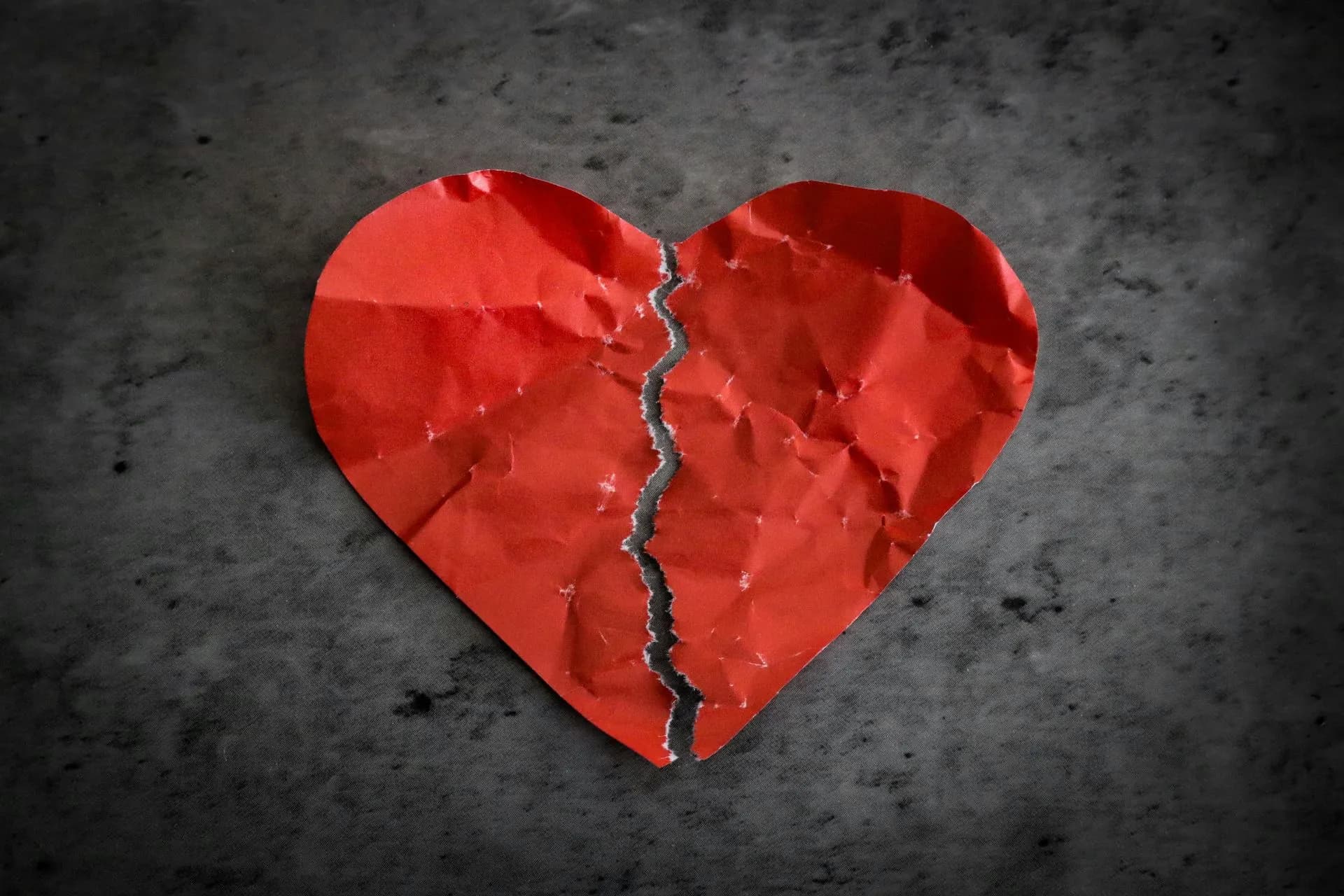 Crumpled red paper heart torn down the middle