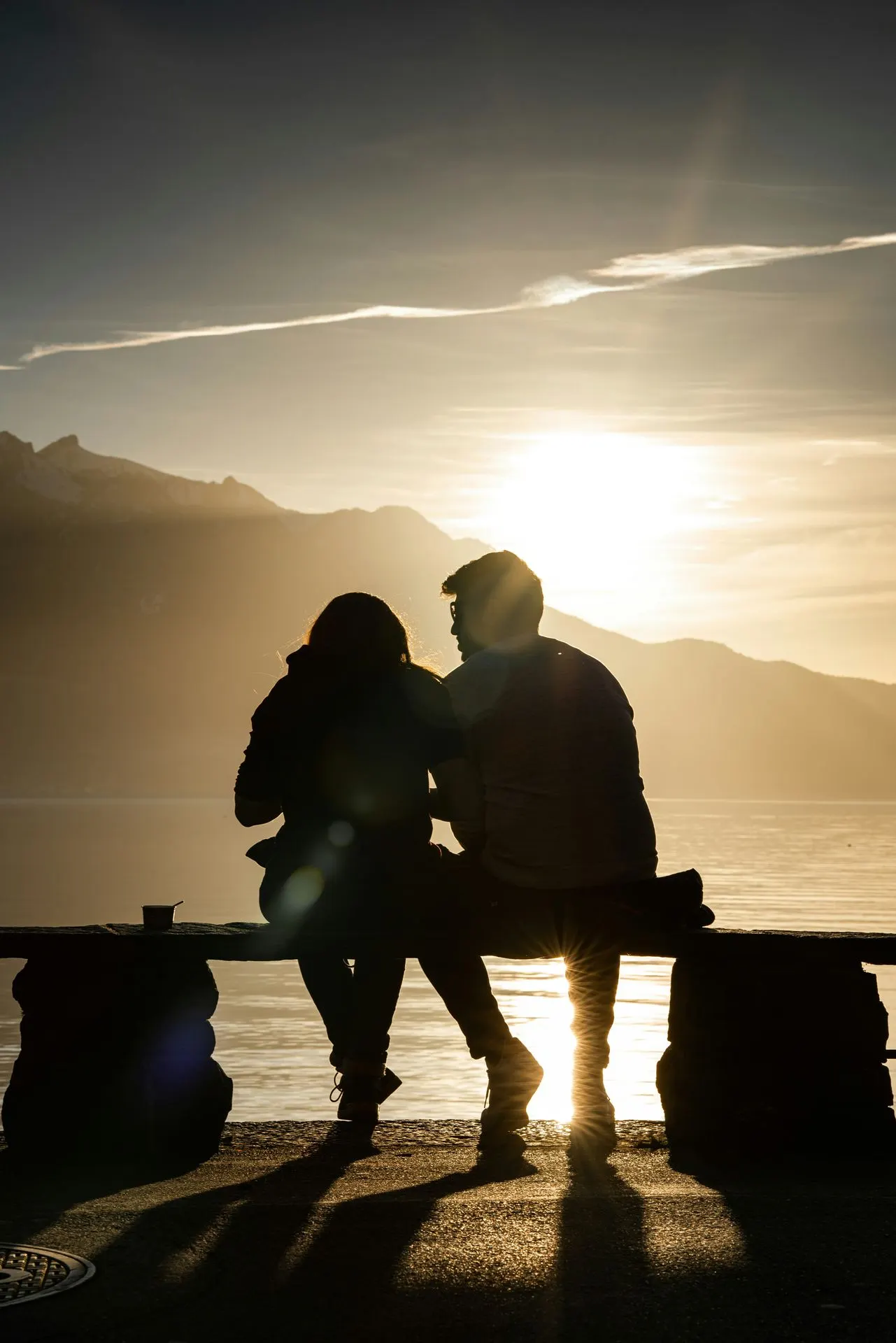 Couple sitting together on a bench watching the sunset