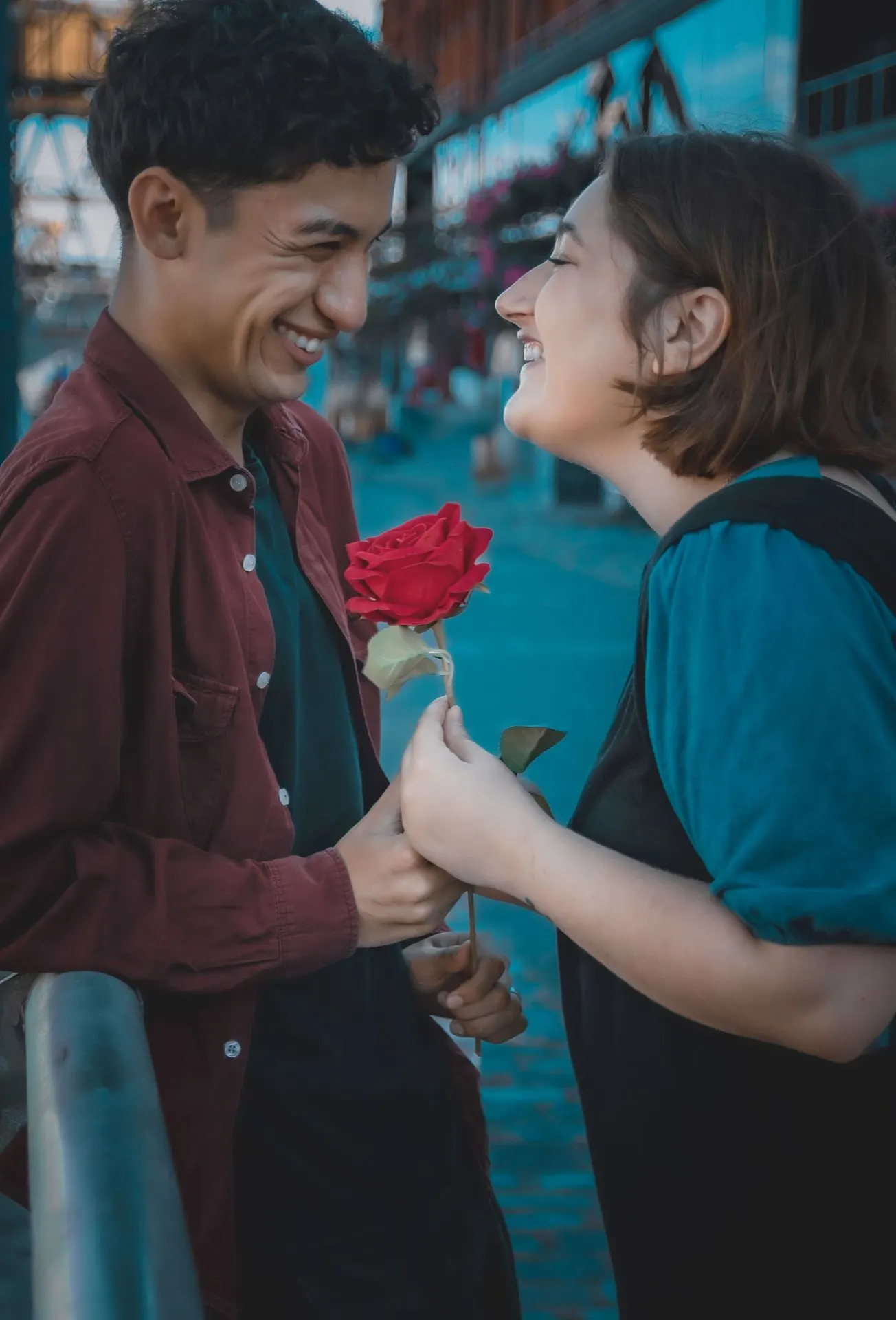 Couple laughing together while one holds a red flower