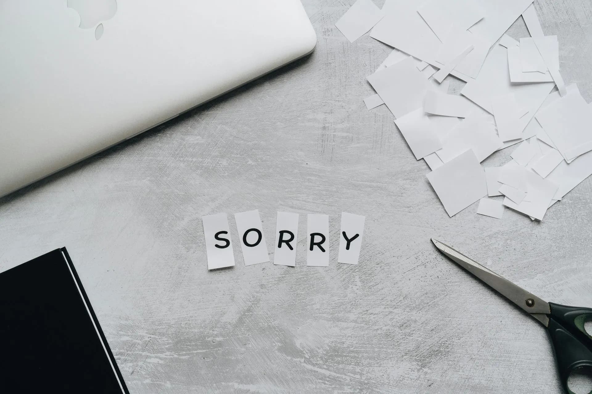 The word sorry spelled out in paper letters on a desk